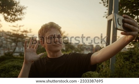 Handsome Blond Young Man Taking Selfies with His Smartphone, Striking Various Poses Outdoors