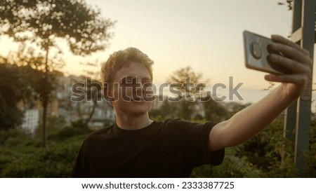 Blond Young Man Taking Selfies with His Smartphone, Striking Various Poses Outdoors