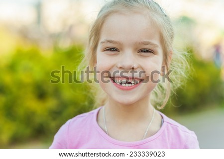 Portrait of beautiful smiling little girl in green summer city park.