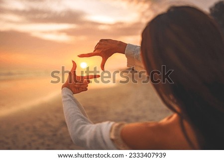 Travel planning concept, Close up of tourist woman hands making frame gesture on the sea beach with sunset, Female capturing the sunrise.