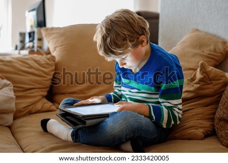 School boy with tablet computer. Schoolchild study online. Electronic device for learning, studying and playing at home. Little boy with laptop pc. Gadget and screen time for children. Kid at home. Royalty-Free Stock Photo #2333420005