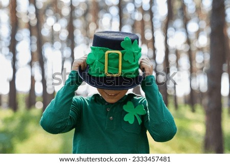 Cute little boy wearing a leprechaun costume on Saint Patricks Day. Portrait of a funny white kid dressed in green clothes decorated with clover leaf