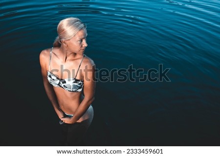Woman goes into the river for a swim. Her body language showing that she feels cold