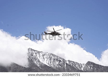 Helicopter against a backdrop of white thick clouds and ice caps. The vast expanse of the clouds and the majestic ice caps showcase the grandeur of nature from a unique perspective. 