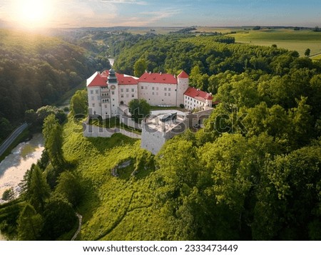 Traveling Poland concept: Aerial view of Pieskowa Skała Renaissance castle, standing on Little Dog's Rock  limestone cliff in the green forest valley of river Prądnik. Summer, sunset, sightseeing. Royalty-Free Stock Photo #2333473449