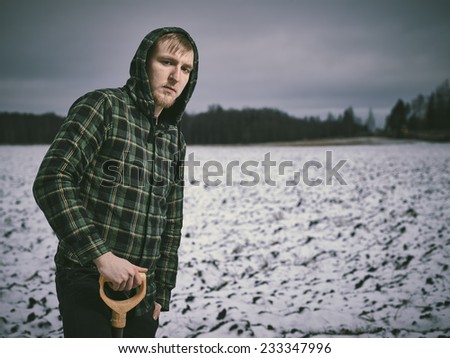 Handsome young man and shovel, snowy plowed field on background - cross processed image