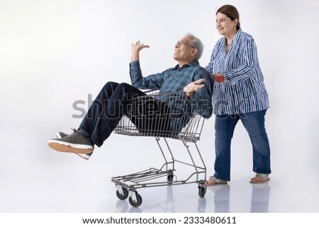 Smiling Senior Man Carrying Happy senior Woman in Shopping Cart on the White Background.