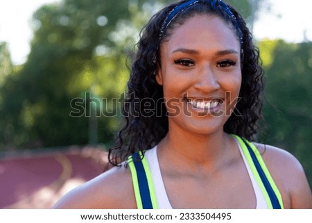 Portrait of happy biracial female basketball player wearing white blue tshirt at basketball court. Sport, activity and lifestyle, unaltered.