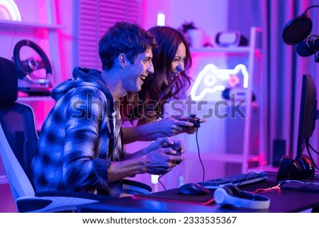 Caucasian Esport couple gamer playing online video game on computer. Handsome man gaming player feel happy and excited, enjoy technology broadcast live streaming while plays cyber tournament at home