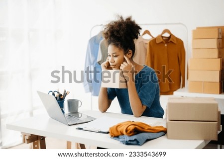 Young African business owner woman prepare parcel box and standing check online orders for deliver to customer on tablet, laptop Shopping Online concept.
