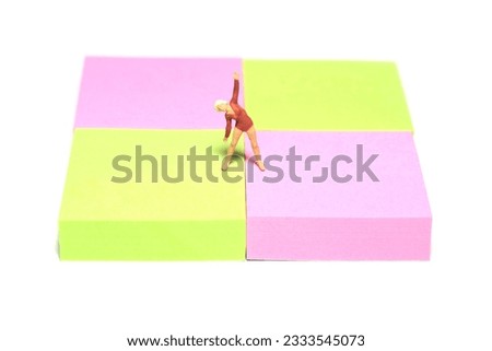Creative miniature people toy figure photography. Sticky notes installation. A woman doing yoga on a mat. Isolated on white background. Image photo
