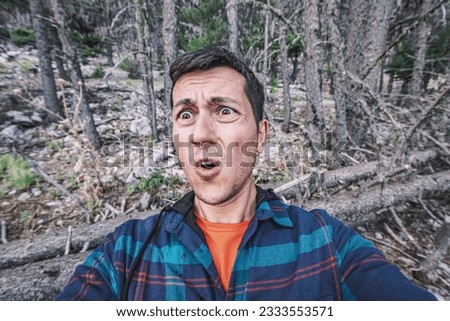 A frightened and lost male hiker looks around in the forest. The concept of meeting wild animals and phobia and accident in the woods Royalty-Free Stock Photo #2333553571
