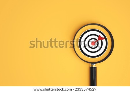 Target board inside a magnifying glass. concept of business idea Focusing and finding goals to set objectives to success or target analysis with copy space Royalty-Free Stock Photo #2333574529
