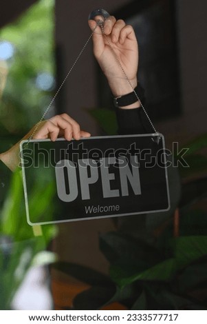 Cropped image of man coffee shop or restaurant owner turning Open sign on the entrance door