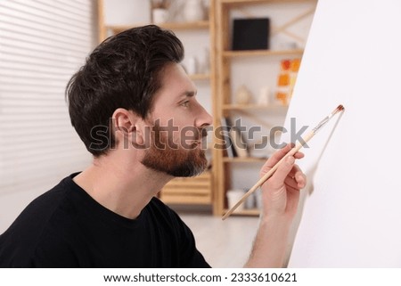 Man painting on white canvas in studio
