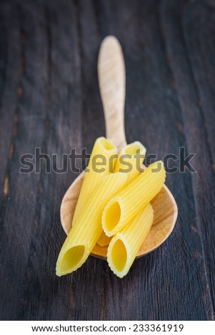 Raw pasta on spoon on wooden background - process old style pictures