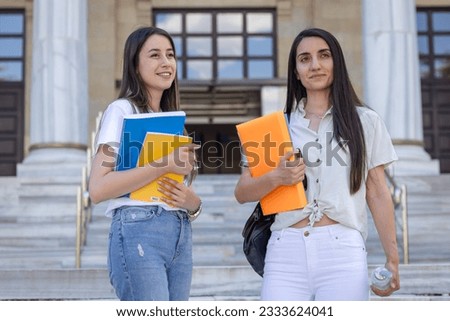 Books in Hands of Two Schoolgirls on University Campus