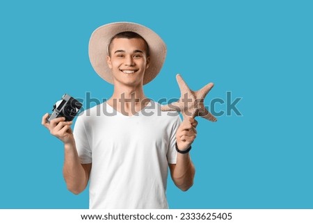 Teenage boy with photo camera and starfish on blue background