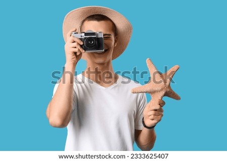 Teenage boy with photo camera and starfish on blue background