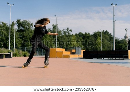 sporty girl rides roller skates in park on city background Active girl in enjoys roller skating lesson street Street sports concept