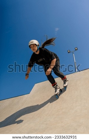 young skilled woman rollerblading and jumping on the ramp in the skate park outside Practicing her tricks or technique of rollerblading competition