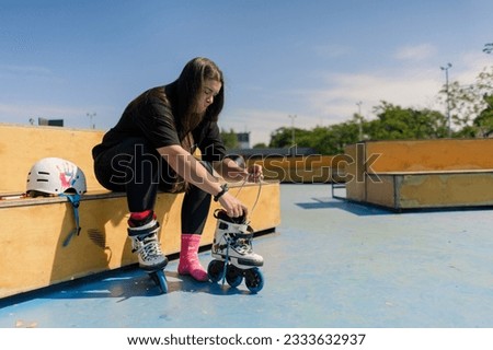 young hipster girl wearing roller skates tying laces skate park before skating street extreme sport