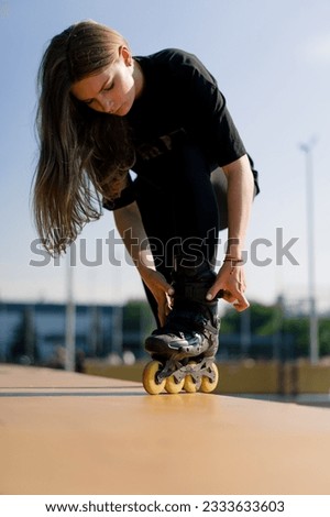 young beautiful girl in park tying laces on roller skate before skating workout active lifestyle hobby