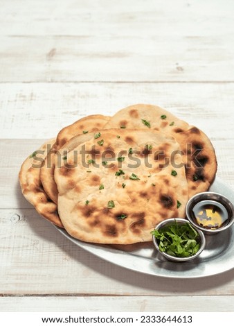 Fresh naan bread on white wooden background with copy space. Several perfect naan flatbreads over metal tray. Vertical