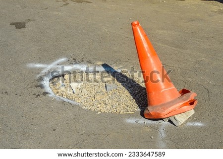 a traffic cone placed near a pothole as a sign