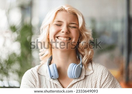Authentic portrait of smiling cute school girl with eyes closed wearing wireless headphones. Technology, positive lifestyle concept