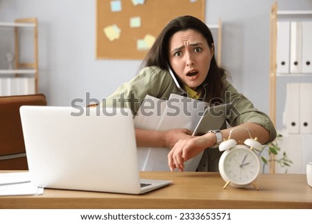 Stressed young businesswoman working under deadline in office Royalty-Free Stock Photo #2333653571