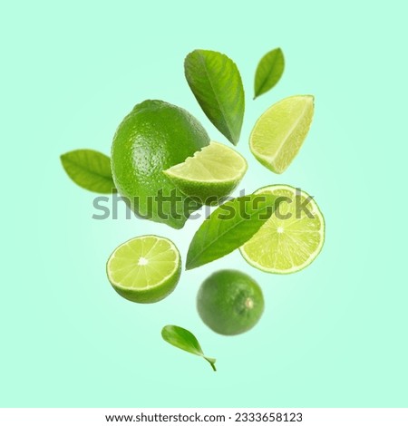 Fresh lime fruits and green leaves falling on aquamarine background