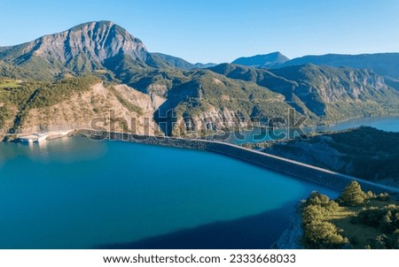 Aerial photography by drone of the Serre-Ponçon Dam at the Serre-Ponçon lake and its mountains, located in the Hautes-Alpes in France