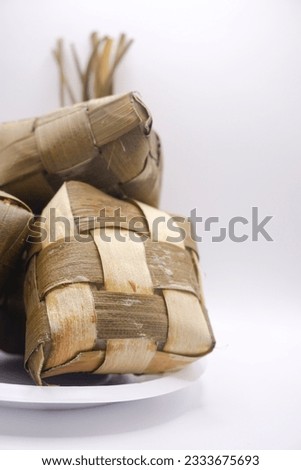 three ketupat on a white paper bowl, photo taken from the side, portrait, selective focus