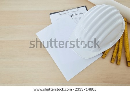 Construction tools and a white hard hat with a measuring stick, paper house building plan on a wooden work table copy space for text Royalty-Free Stock Photo #2333714805