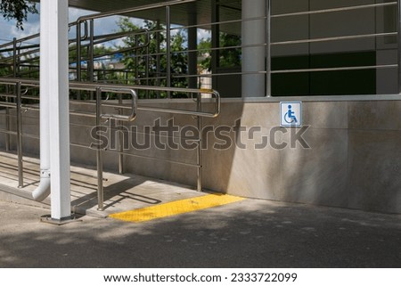 Street ramp for people with disabilities in a wheelchair. Entrance to the building with handrails and to help handicapped people. Tactile slab and wheelchair sign