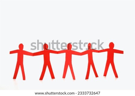 Red cutout paper men standing holding hands.