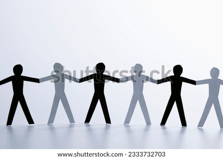 Black and white paper cutout men standing holding hands together.