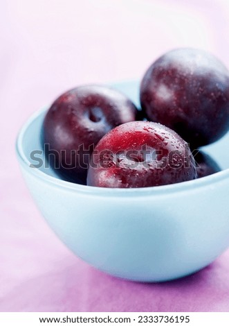 fresh plums in lightblue bowl