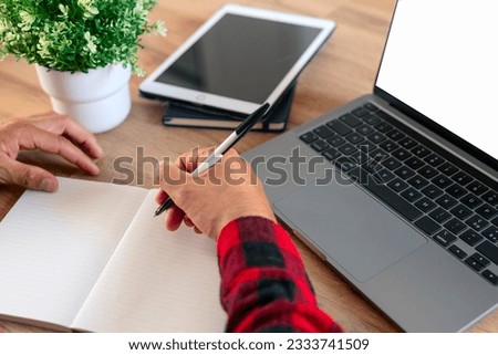 student using laptop and writing notes.