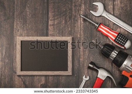 Construction tools and a frame with an empty black blank on a wooden background. The concept of celebrating Labor Day, May 1, Father's Day, Builder's Day.