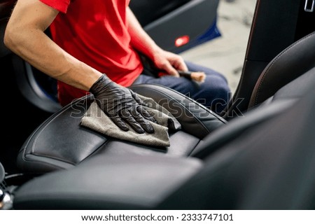 Detailing a man an employee of a car service station performs chemical cleaning and washing of a car with microfiber cloth Royalty-Free Stock Photo #2333747101
