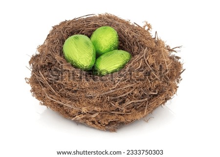 Chocolate easter eggs in a natural bird nest wrapped in green foil, over white background.
