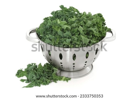 Kale green cabbage in a stainless steel colander and loose, over white background.