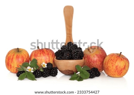 Blackberry fruit in an olive wood ladle with gala apples and loose blackberries with flower leaf sprigs isolated over white background.