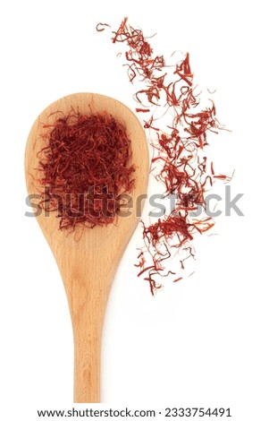 Saffron spice threads in a wooden spoon and scattered isolated white background.