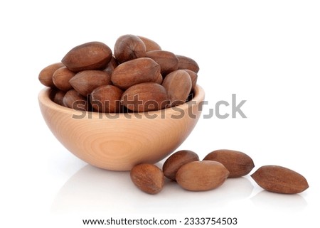 Pecan nuts in a beech wood bowl and loose isolated over white background.