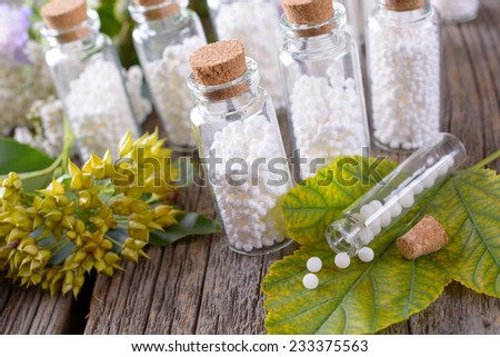 Homeopathic lactose sugar globules in glass bottles with plants Royalty-Free Stock Photo #233375563
