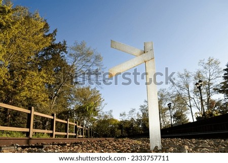 Blank sign on railway under blue sky in forest.