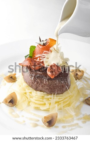 The chef pours sauce over the steak. A piece of steak with mashed potatoes, mushrooms and sauce